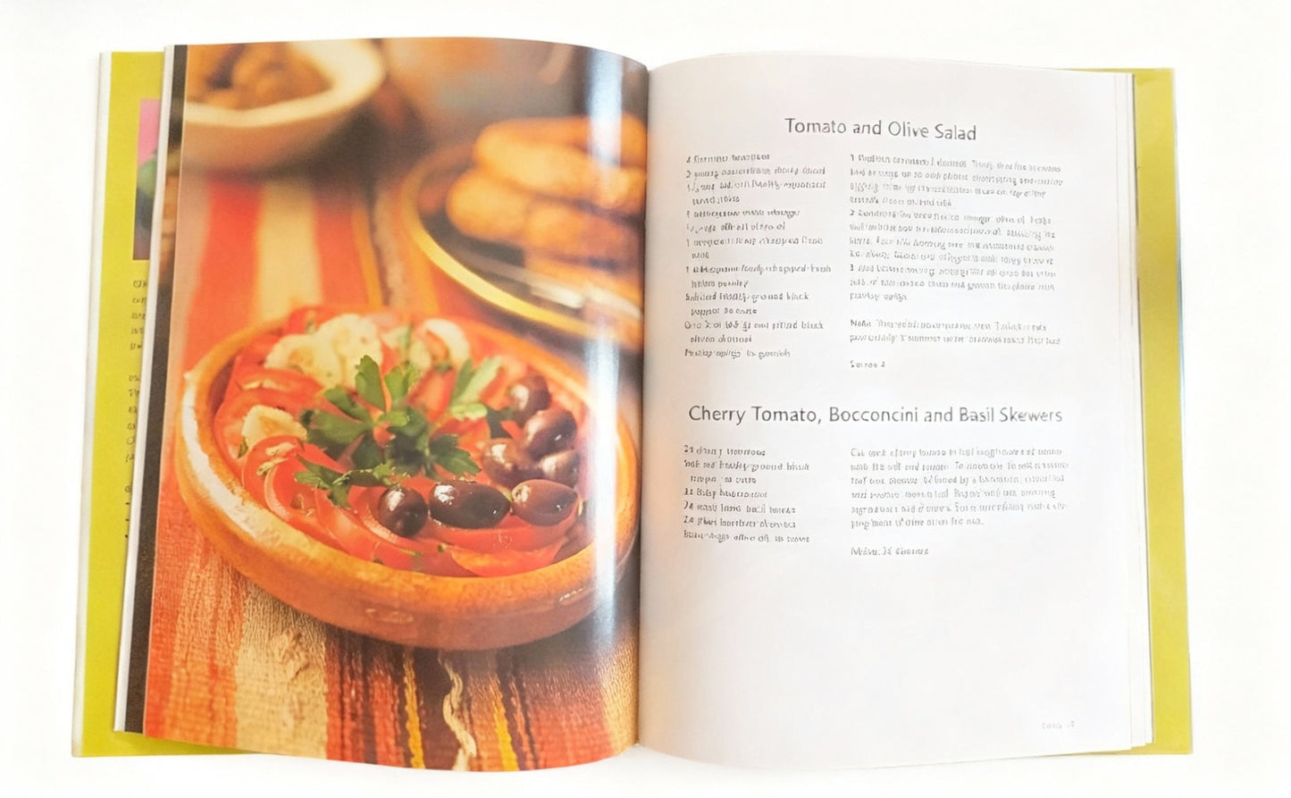 Open cookbook showing a recipe for Tomato and Olive Salad with an image of the dish on the left page.