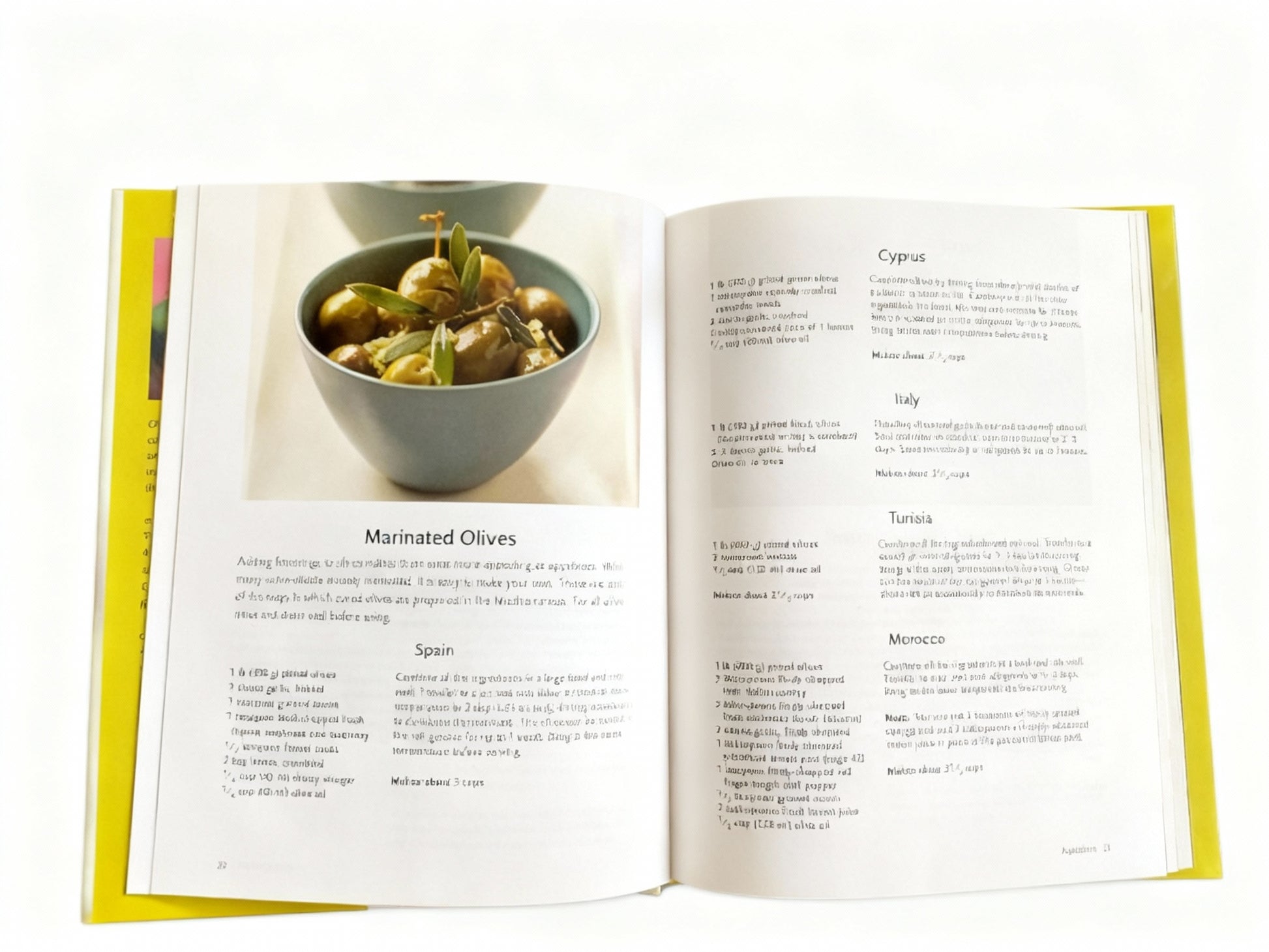 Open cookbook showing a page with a picture of marinated olives and text.